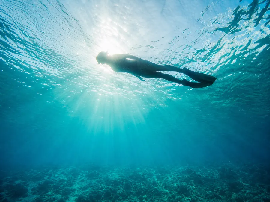A relaxed snorkeler floating at the surface in bright sun rays